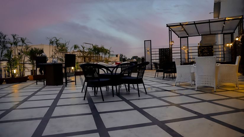 A rooftop terrace with tables and chairs, offering a beautiful view and an ideal setting for outdoor dining at sunset - Clarks Inn Express, Near Jammu Bari Brahmana Railway Station