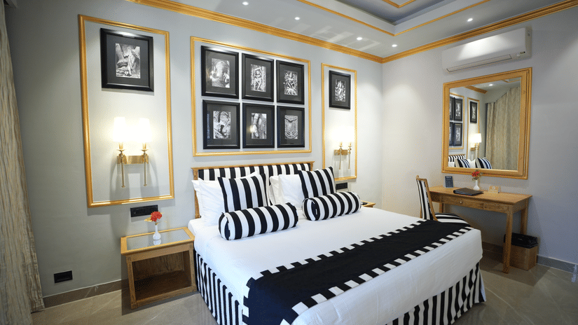 An Executive Suite bedroom at Clarks Khajuraho with a neatly made bed, patterned bedding, framed artwork above the headboard, and side lamps.