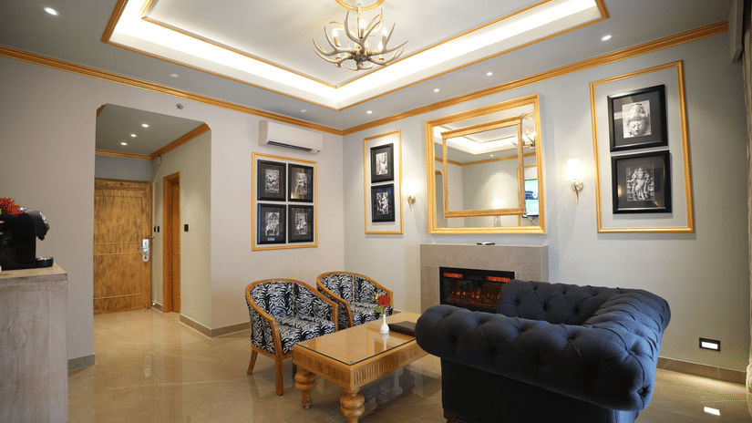 An Executive Suite living area at Clarks Khajuraho with cushioned seating, a center table, framed wall art, and a well-lit ceiling design.