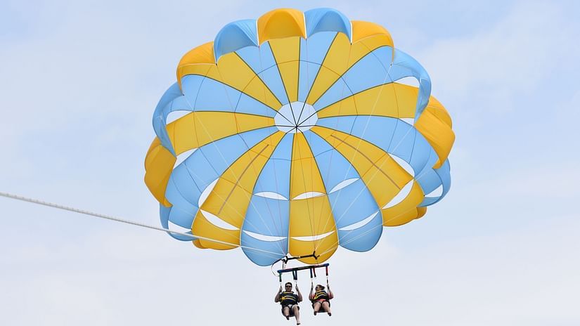 An overview of a couple parasailing together on a clear blue sky.