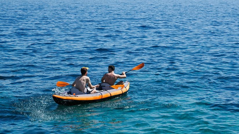 An overview of two men in a kayak, travelling on a waterbody.