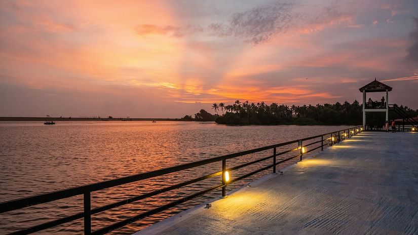 bridge kerela - lined by small lights along the walkway and a light house in the distance.