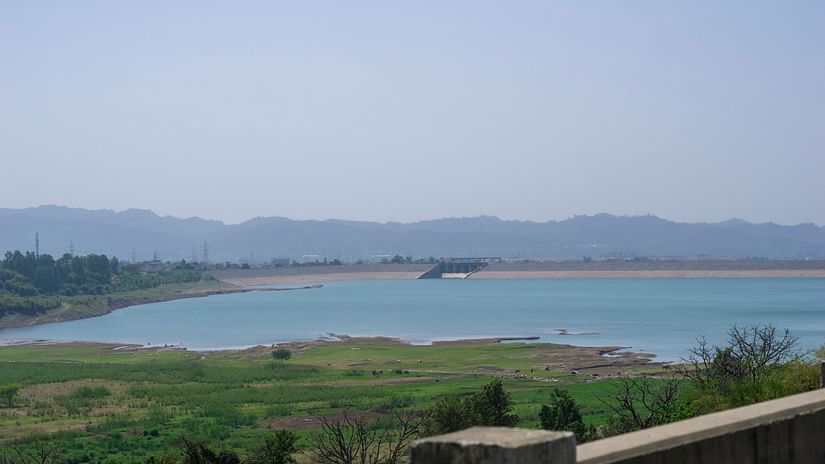 an overview of dam with mountains in the background and green cover in the foreground