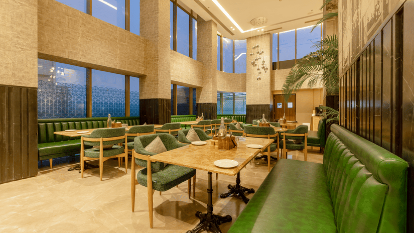 Tulipe restaurant setup with wooden tables, upholstered chairs, and a long leather booth at Golden Tulip - Sector 80, Gurugram