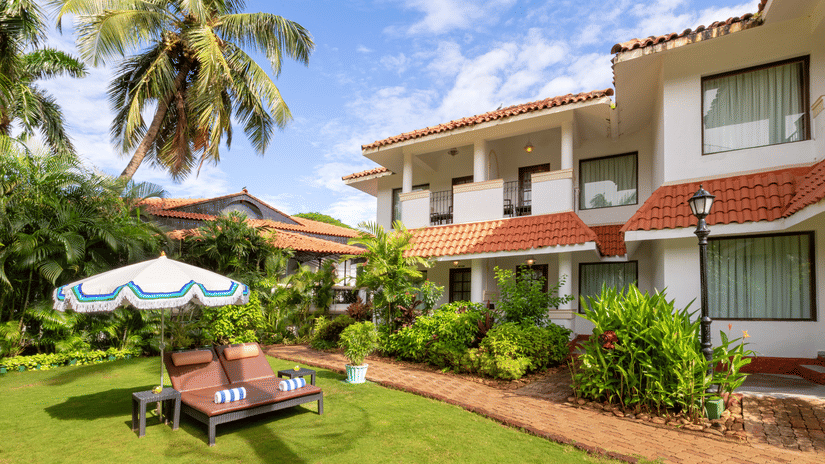 Heritage Village Resorts & Spa, Goa features lush gardens, sun loungers, and charming Portuguese-style architecture.