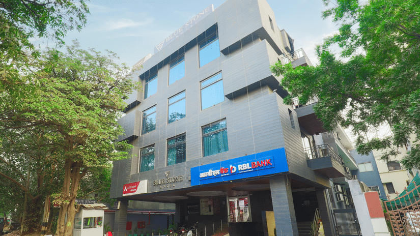 Modern glass-and-steel exterior of Hotel Bluestone (Nehru Place) by The Cosy Hotels set among leafy trees in Nehru Place