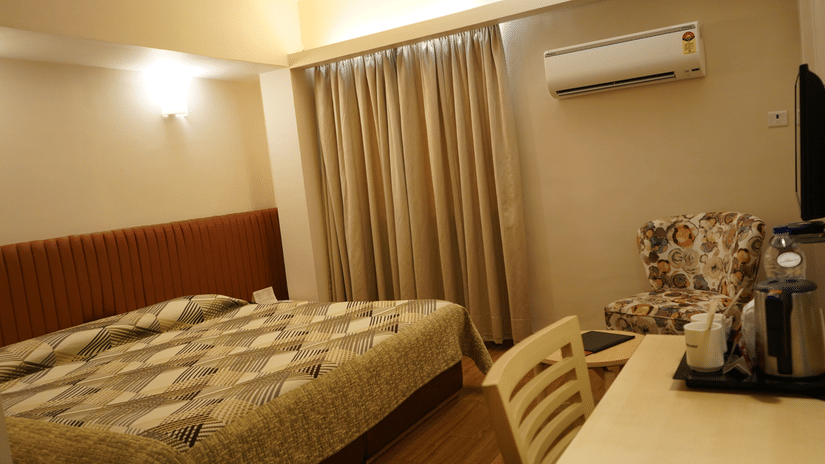 A room with a large bed with spreads, pillows, a table, and cushions | Hotel Diplomat