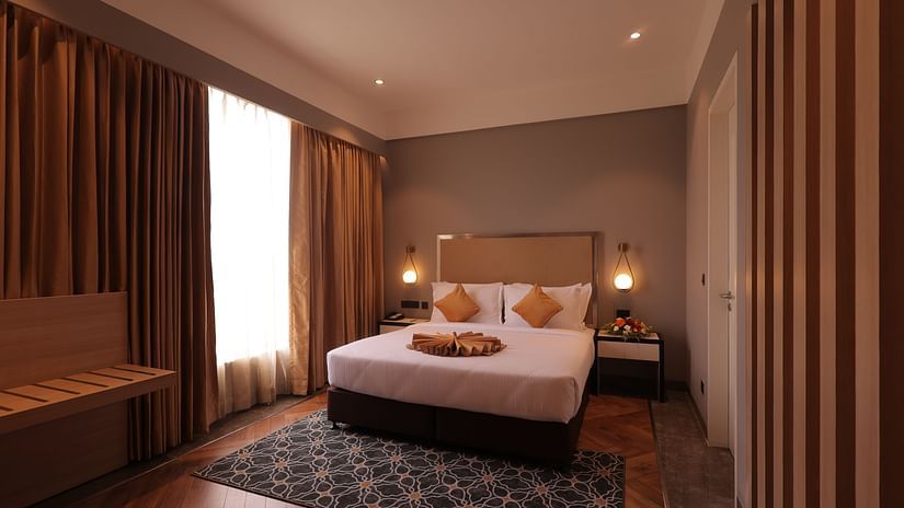 Overview of the Executive Suite with a king bed, side tables, lamps and curtains covering the floor to ceiling window - Polo Towers, Agartala