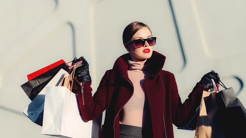A woman holding many shopping bags and posing for a picture
