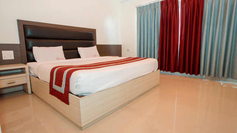 Interiors of an Executive Room in Hotel Shompen, one of the best places to stay in Port Blair, featuring a large bed and a large window with curtains closed.