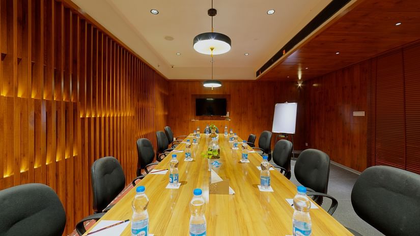 A modern and well-equipped meeting room at Icon Boutique Hotel by Bhagini, Domlur, with a long conference table, chairs, and a wooden wall.