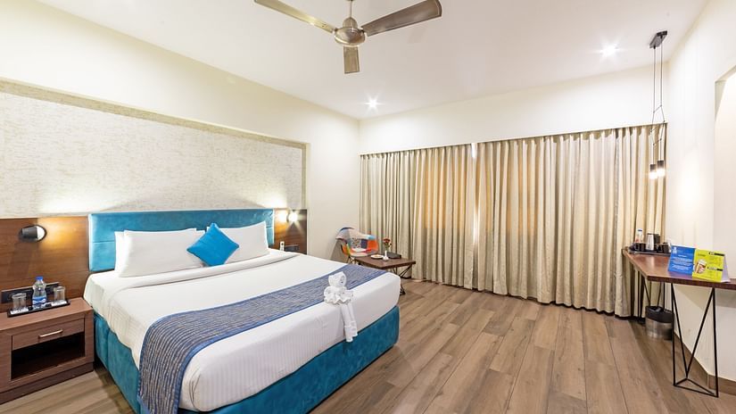 A spacious and well-lit hotel room at Icon Boutique Hotel by Bhagini, Domlur, with a comfortable bed, a work desk, and a seating area.