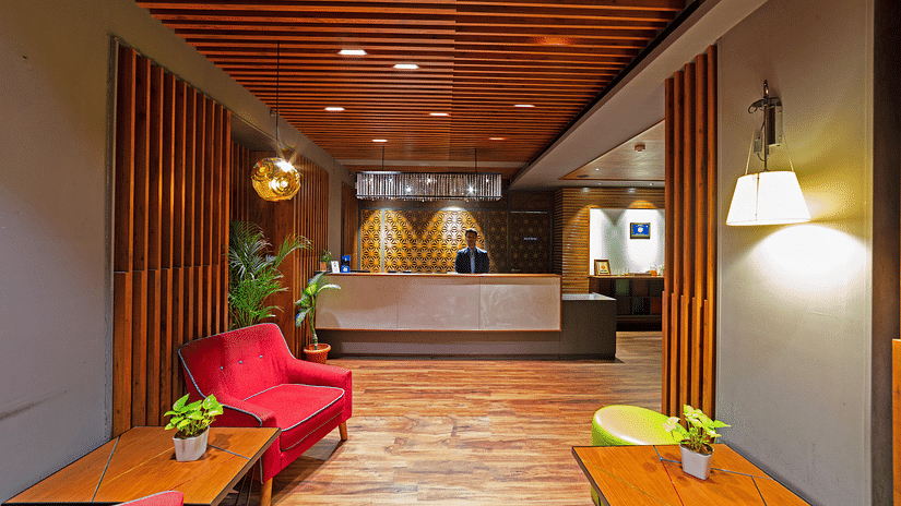 The welcoming lobby of Icon Boutique Hotel by Bhagini, Domlur, featuring a wooden ceiling, comfortable seating, and a reception desk.