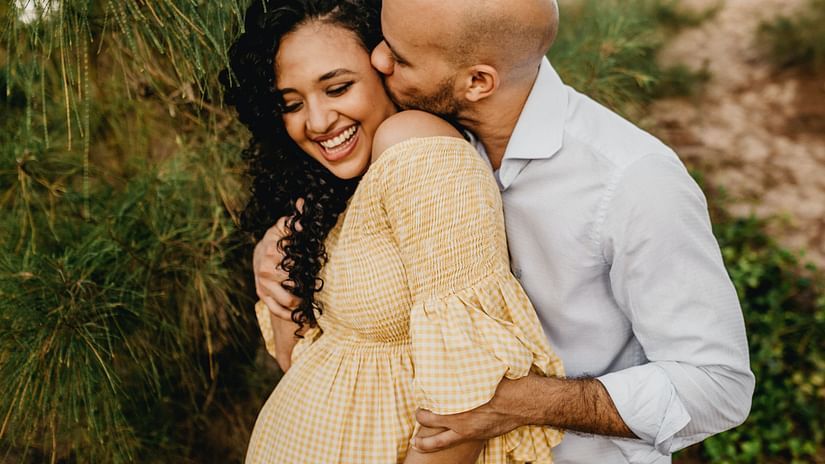 A man kisses and embraces his pregnant wife.