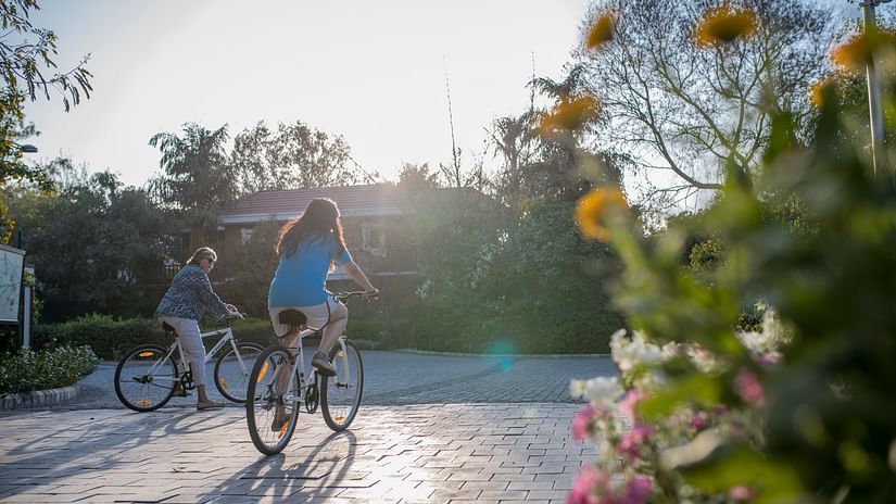 guests cycling on a stone pathway near some flowers at Karma Lakelands.