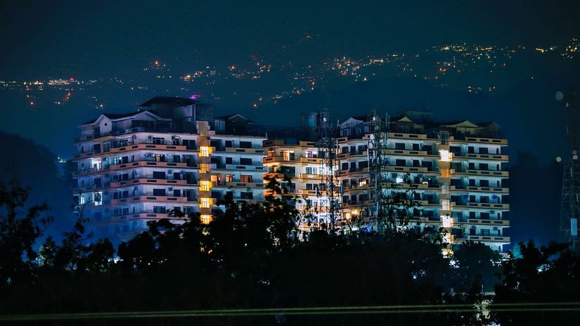 tall buildings lit with sparkling lights captured during the night with mountains as a backdrop