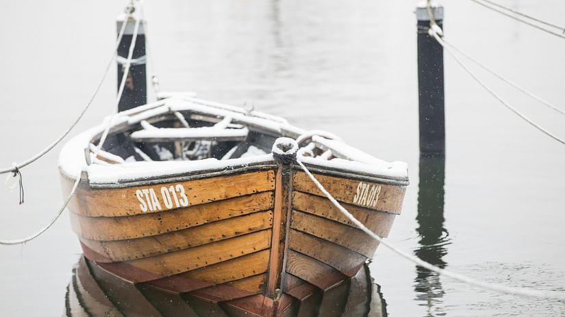 a wooden boat tied on to two wooden logs to not let it wander on the river