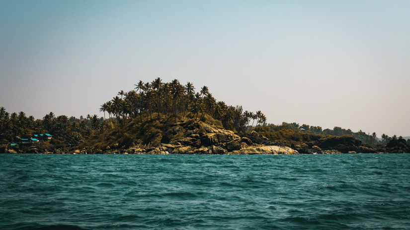 A view from the Arabian Sea of Palolem Beach in the distance with trees also seen. This beach is one of the best attractions in South Goa.