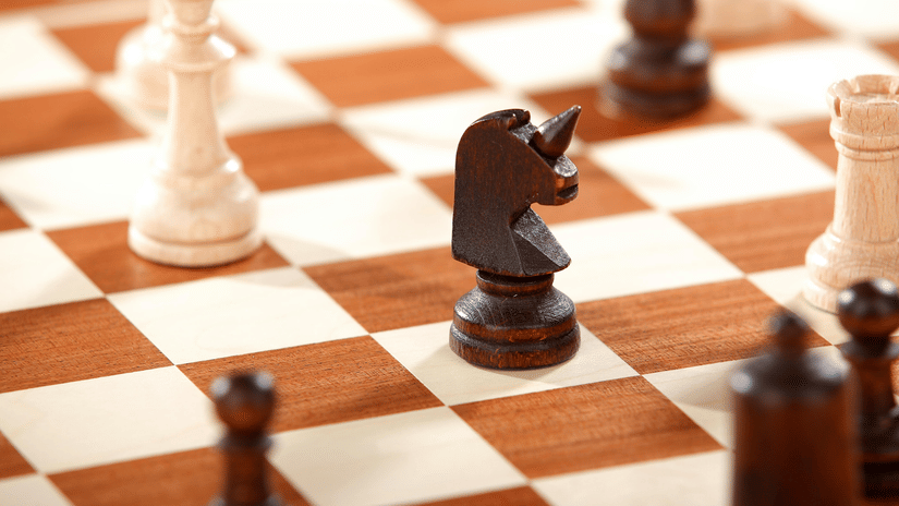 Black knight piece surrounded by white and black chess pieces on a wooden chessboard in a strategic mid-game position.