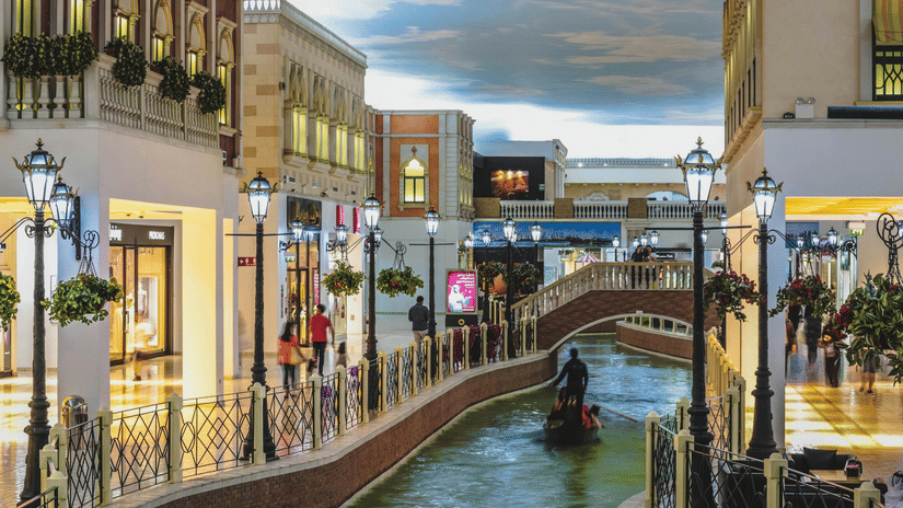 An indoor shopping centre designed like Venice, featuring a canal with a gondola, stone bridges, and street lamps.