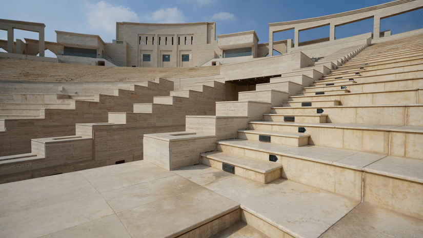 Large outdoor amphitheatre made of light-coloured stone, featuring stepped seating rows and arched buildings in the background.