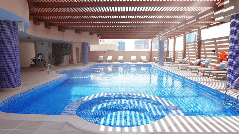 An overview of the swimming pool with sun's rays hitting the pool's surface - La Maison Hotel, Doha.