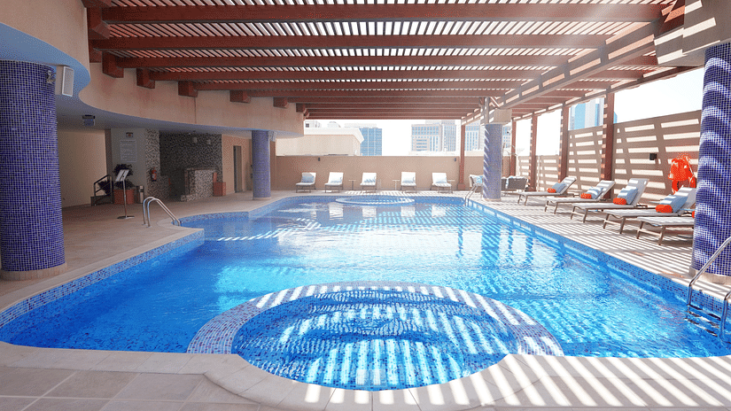 an overview of the swimming pool with sun's rays hitting the swimming pool - La Maison Hotel, Doha.
