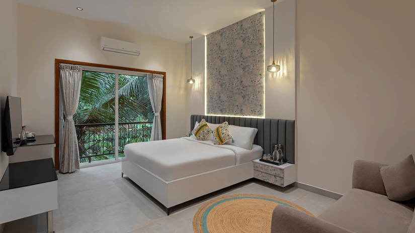 Deluxe room with king bed and large glass doors opening to a garden view at Lamrin Morjim Goa.