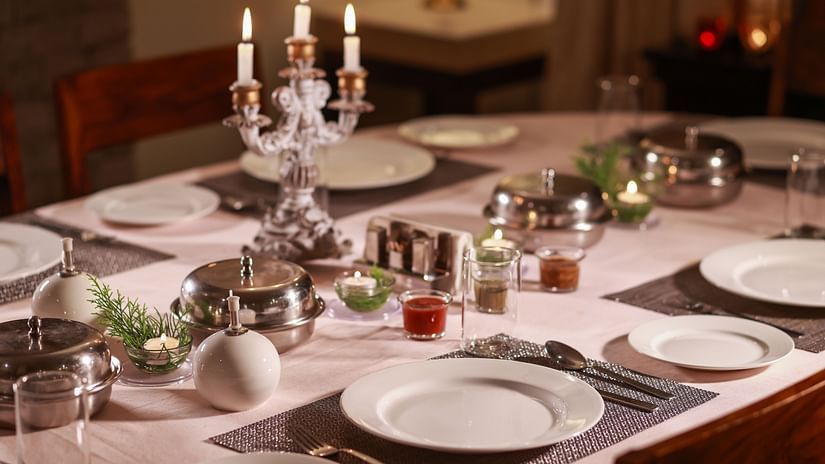  Elegantly set dinner table with candlelight, fine china, and silverware, ready for a formal meal.
