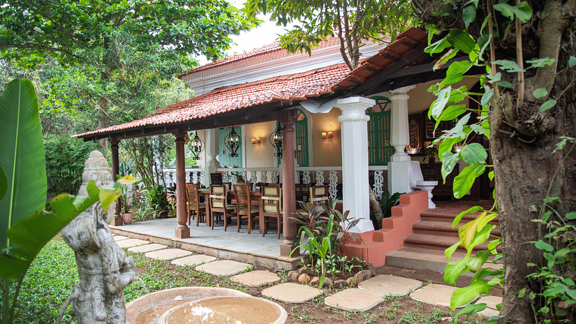 A side view of a cottage style facade image surrounded by trees and plants at Lamrin Ucassaim Hotel, Goa