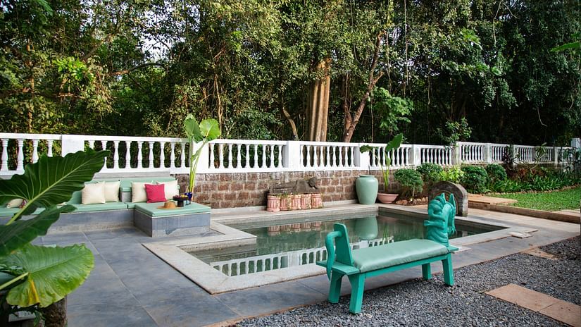 An mage of a plunge pool with a seating arrangements on the side and the entire area is surrounded by trees and plants - Lamrin Ucassaim Hotel, Goa