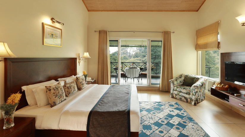 Full angle view of Super deluxe room featuring a balcony overlooking the tea gardens and other room amenities like a television, a tea & coffee maker, among others - Lamrin Norwood Green, Palampur