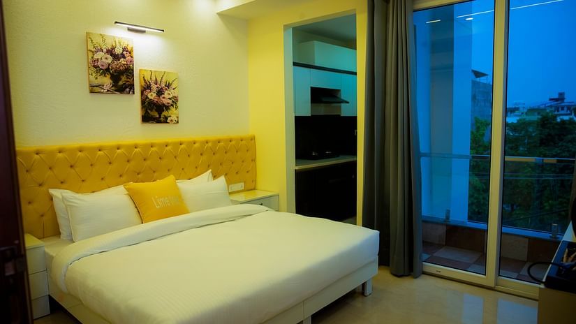 An image of a bedroom with king size bed, photo frames hanged on the wall, and glass door  leading to the balcony - Lime Tree Luxury Studio