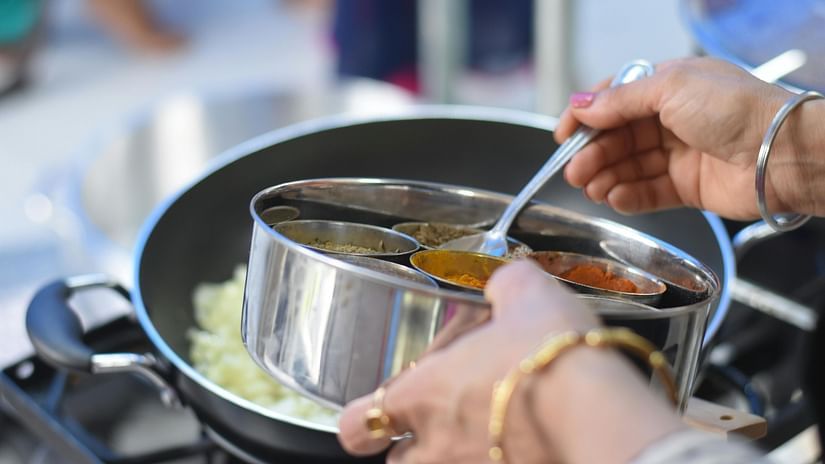 A woman using assorted spices bowl to add in the dish. 