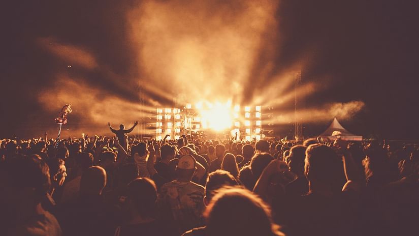 People cheering at a concert with warm lighting and music.
