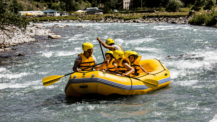 People rafting on a river surrounded by plants and trees.