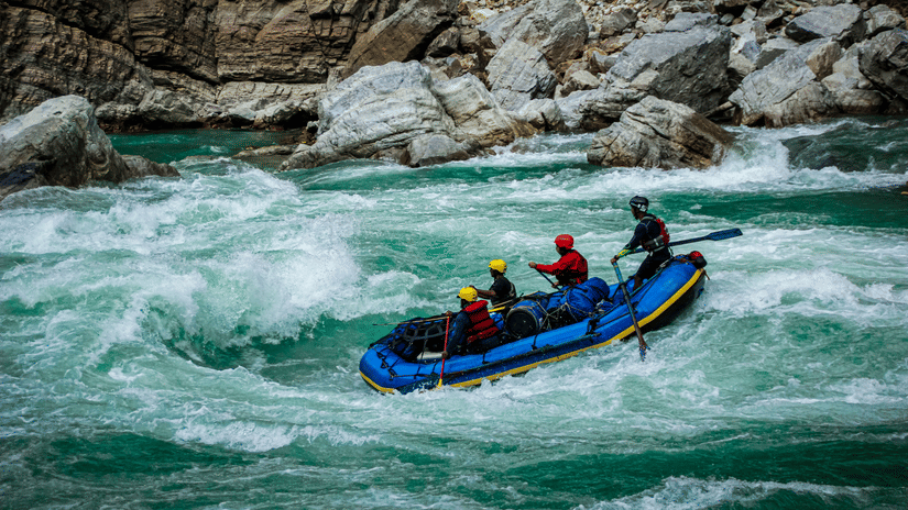 A group of people rafting through fast-moving river rapids in an inflatable boat.