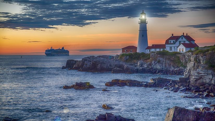 A lighthouse near a beach with a sunset in the background