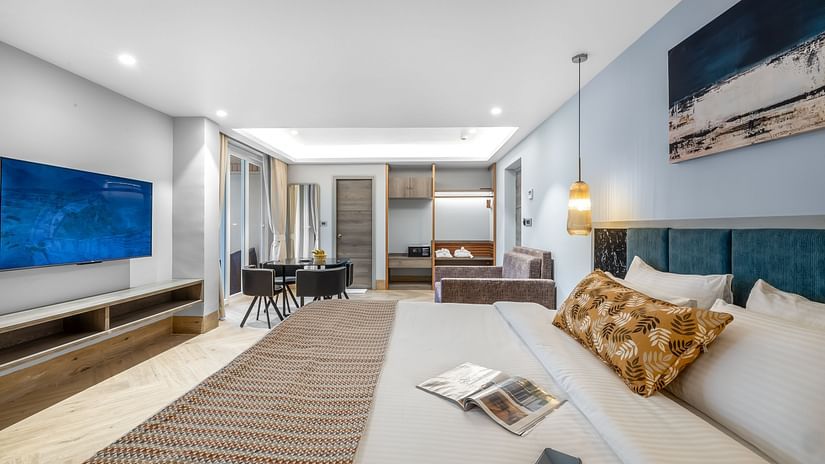 Junior Suite with Bathtub featuring a large bed, lounge area, flat-screen TV, warm lighting, and stylish decor at Ocean Palms Goa