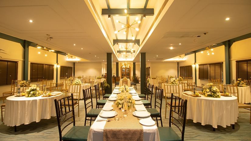 Indoor banquet hall with long dining tables set for an event, elegant centrepieces, and warm ambient lighting. - Polo Floatel, Kolkata