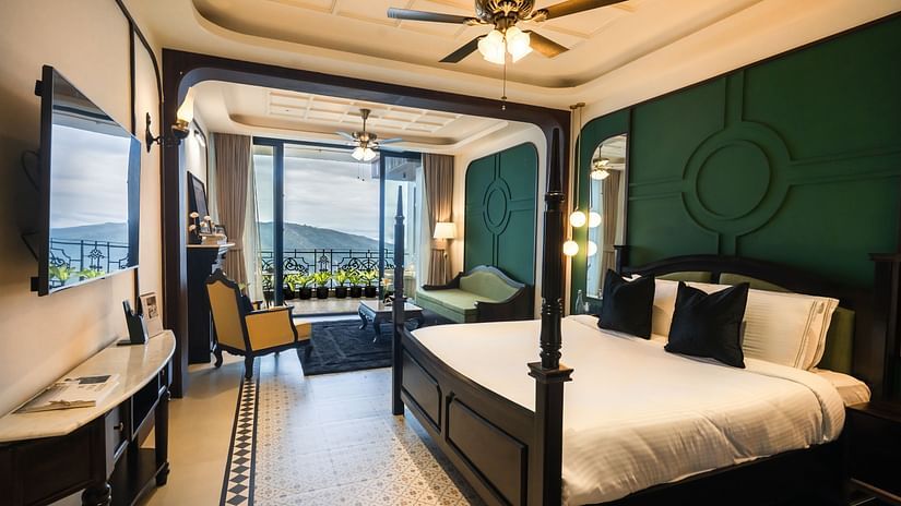 An image of a bedroom with king size bed, flat TV screen, chair, sofa, and a view of the balcony - Polo Orchid Resort, Cherrapunjee
