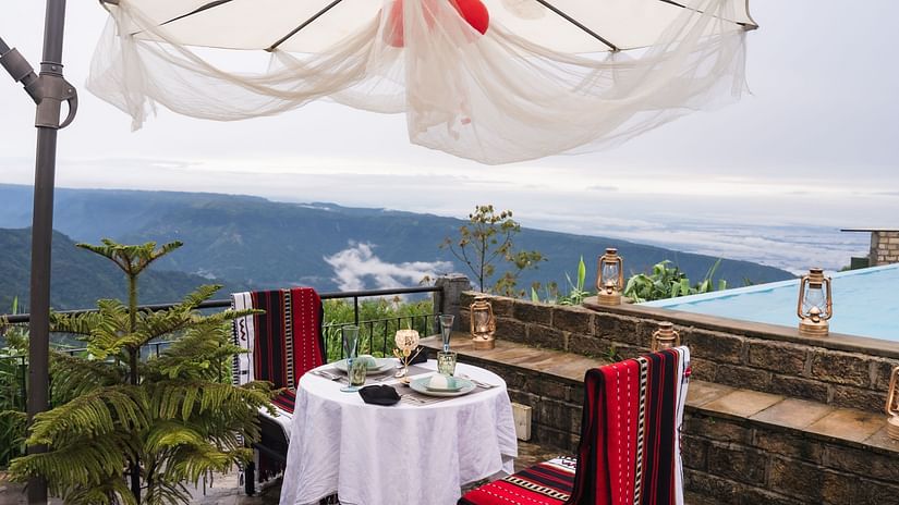 An image of a dining table with two chairs on either side with a view of waterfalls in broad daylight - Polo Orchid Resort, Cherrapunjee