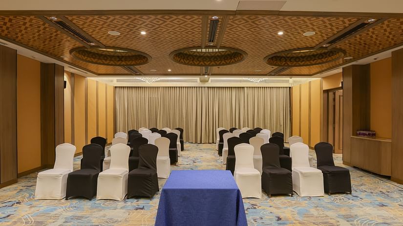 A room with rows of chairs facing a table, possibly set up for a meeting or event - Pride Hotel Pune