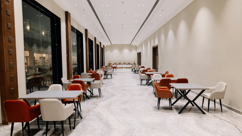 Pride Premier Alwar | A dining space with chairs and tables in a pathway.