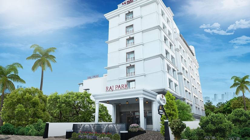 facade image of Raj Park Hotel, Chennai with trees on either side and blue sky in the background