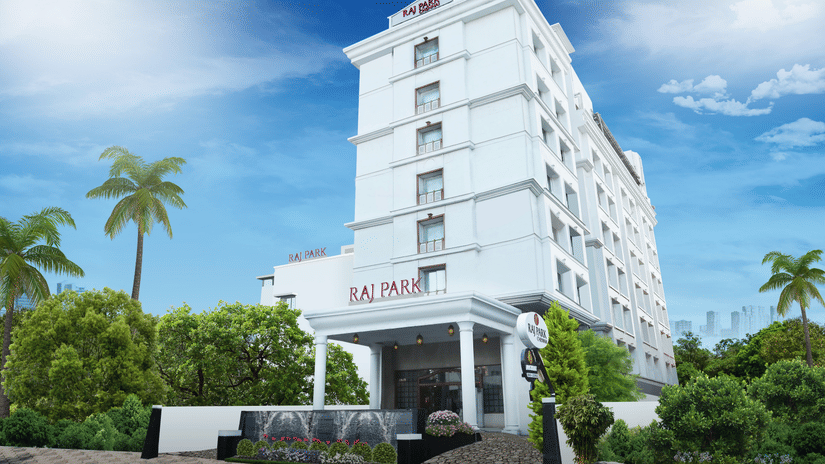 Facade image of Raj Park Hotel, Chennai, with trees on either side and blue sky in the background.