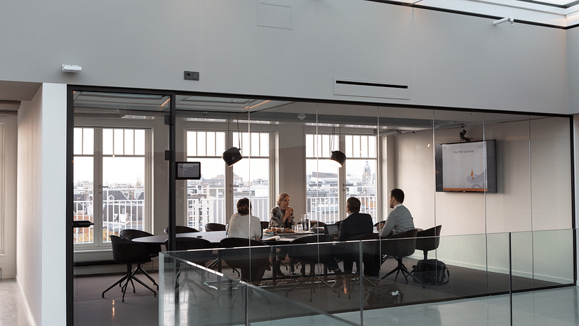 a group of people inside a glass room discussing about something