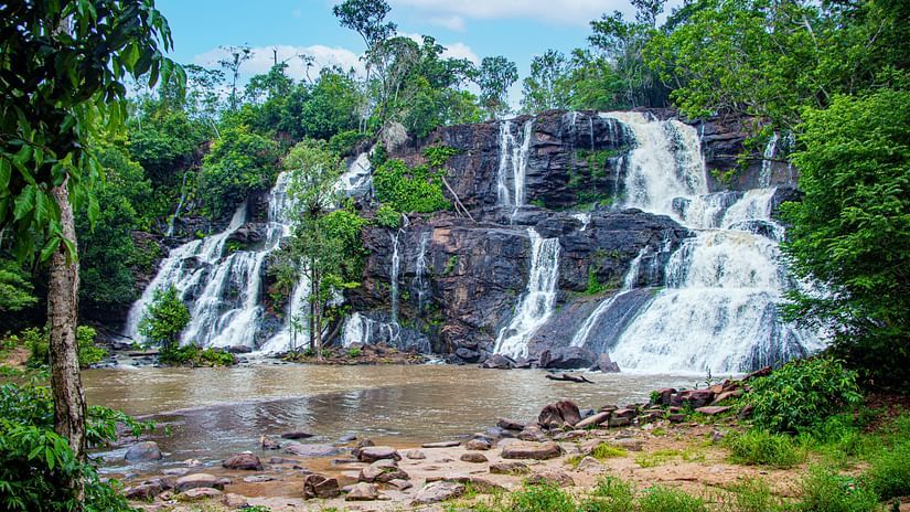 a waterfall cascading on all sides of a rocky mountain with trees on either side
