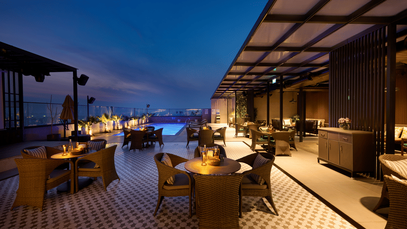 Rooftop lounge at Riviera Sarovar Portico, Pathankot illuminated at night with cosy seating and a vibrant atmosphere for social evenings.