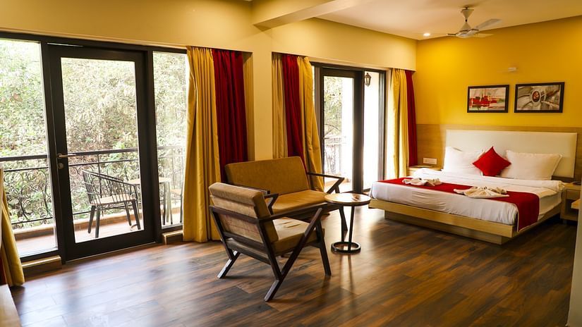 An overview of the Executive Suite with a double bed, chairs and balcony in view - Rosetum Anjuna.